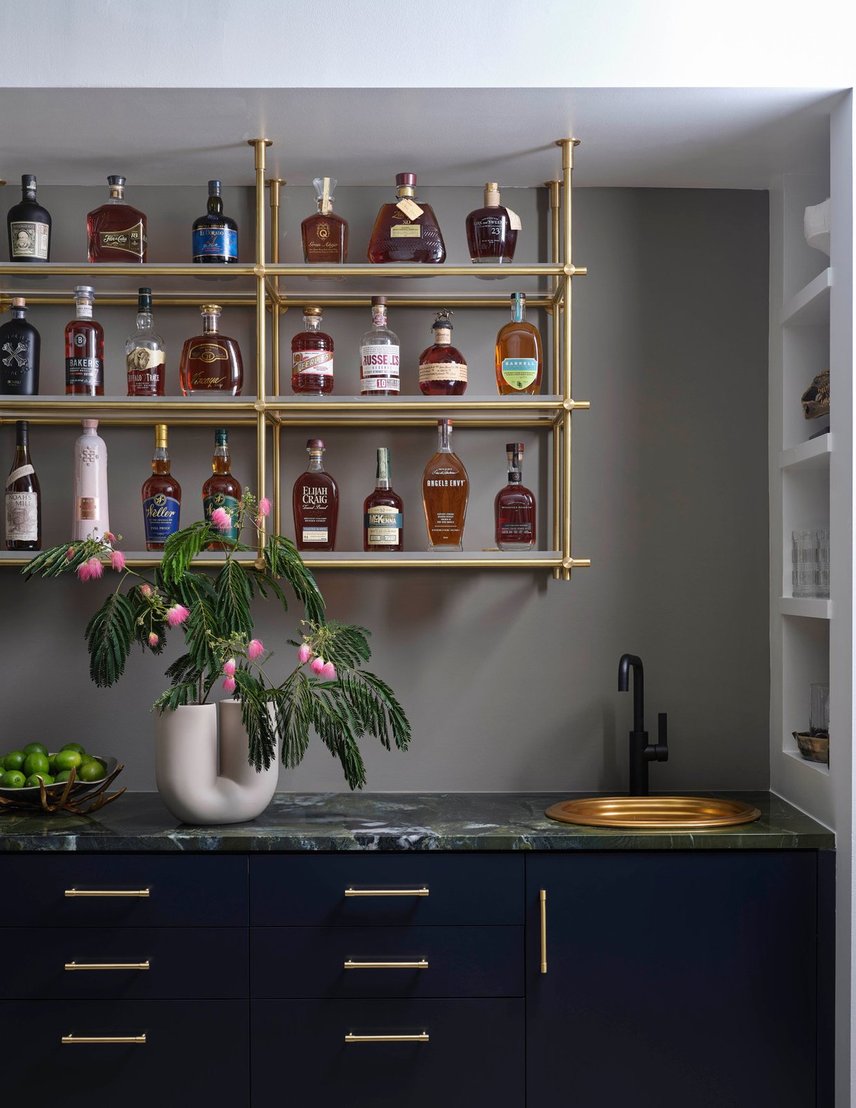 Bar detail at The Dogwood Residence: brass shelves and green marble counter.