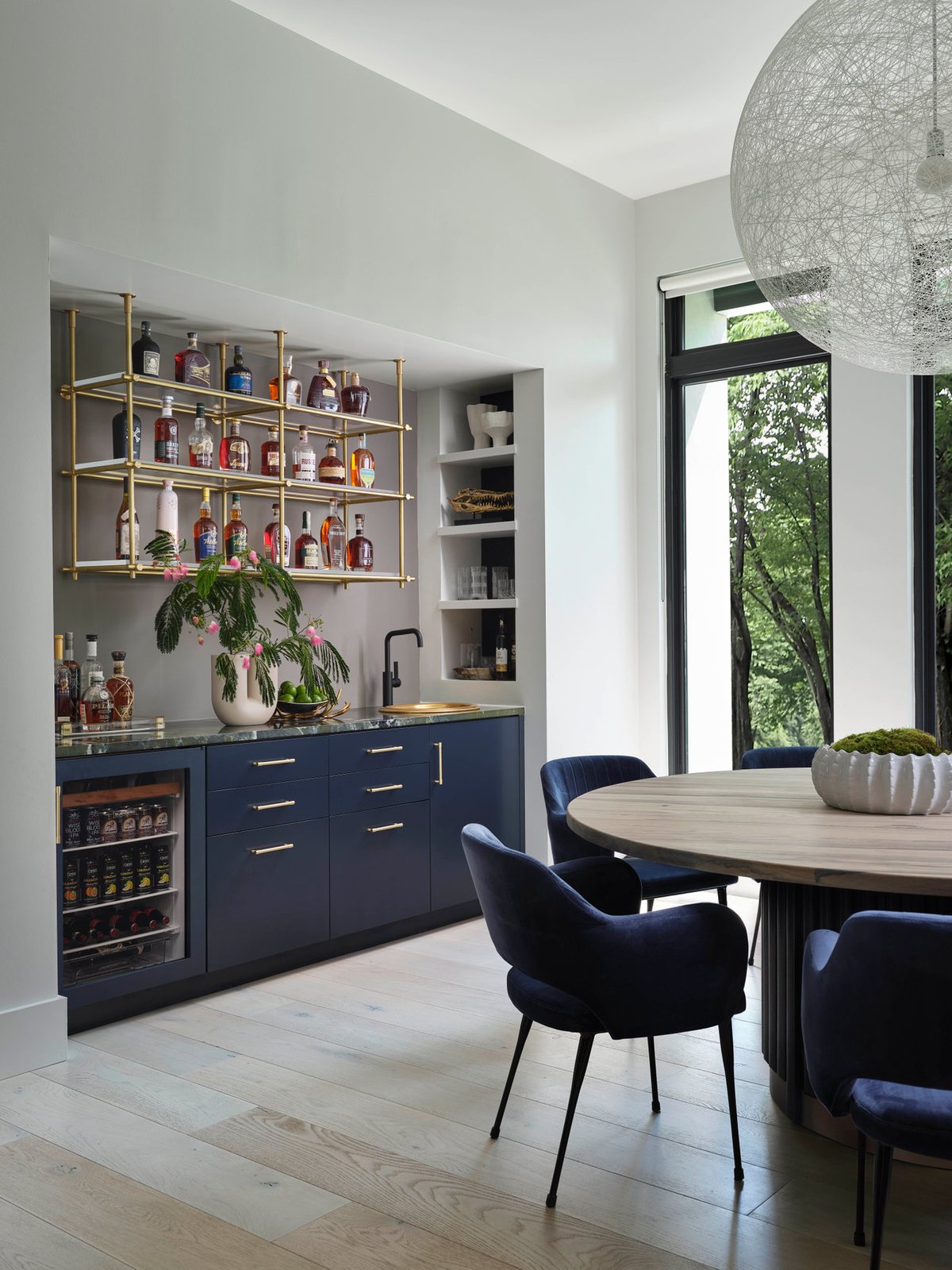 Bar and dining area of The Dogwood Residence with brass shelving and navy cabinetry.