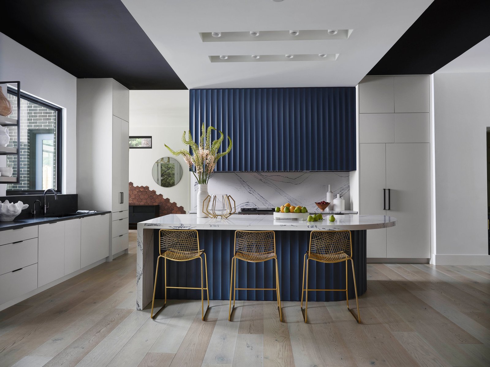 Kitchen of The Dogwood Residence: navy fluted island, white oak floors, marble counters.